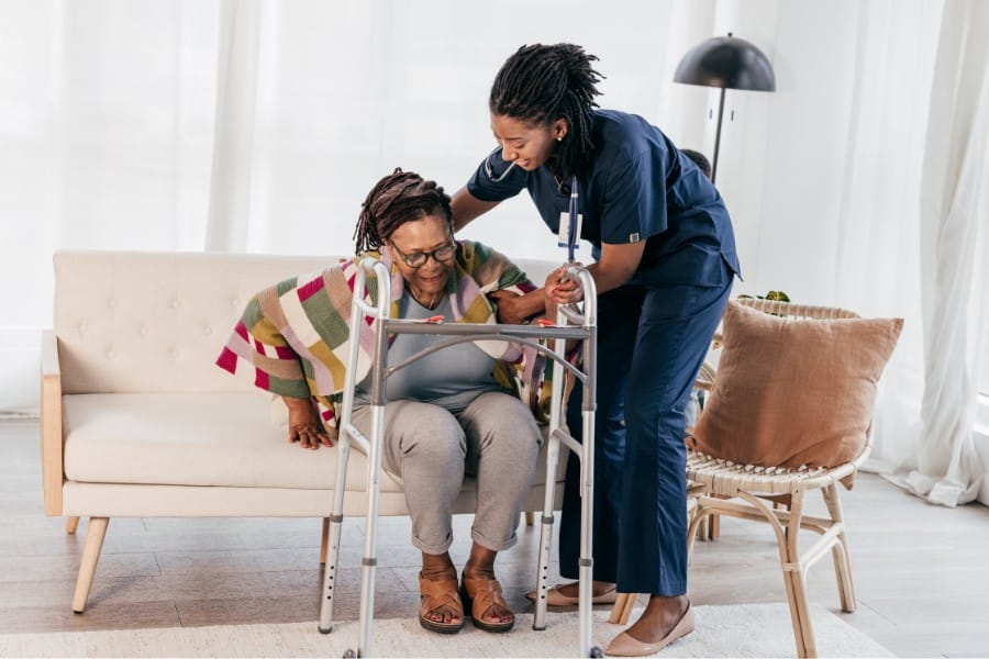 RN assisting her patient getting off the couch