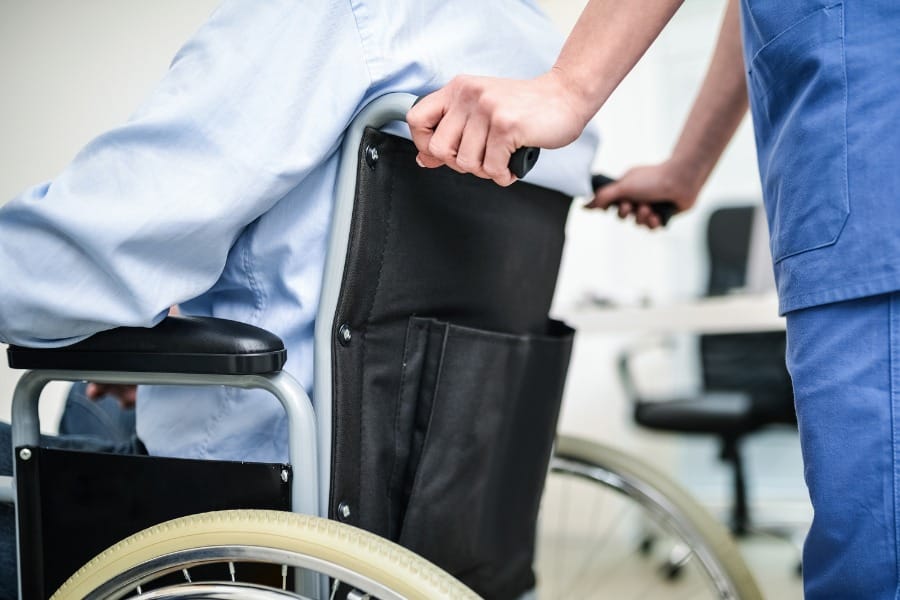 post-op nurse pushing patient in a wheelchair