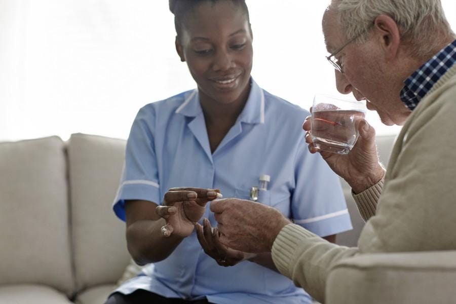 pill assistance at home san carlos ca Smiling nurse assisting a client with medication in San Carlos