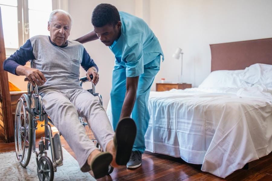 Male LVN assisting his client getting into a wheelchair